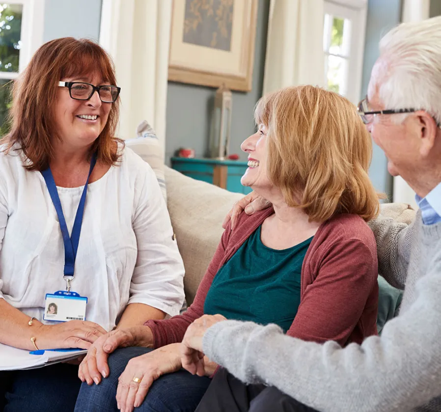 A personal caregiver from Montreal is chatting about personalized care plans with a senior and their spouse.