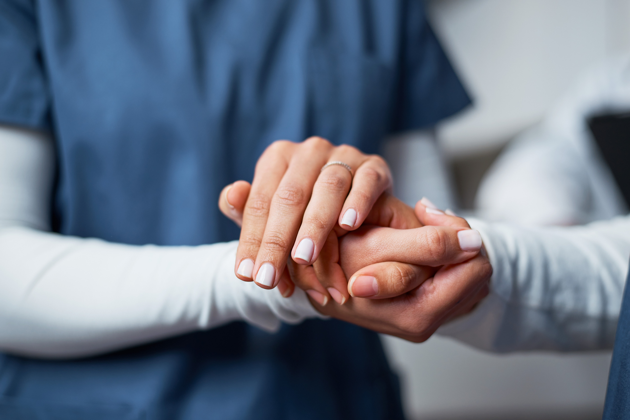A caregiver in scrubs holding a client's hand