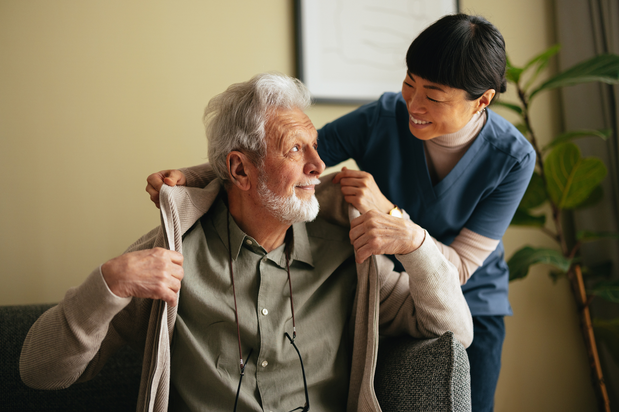 Caregiver helping a client with a sweater, both smiling