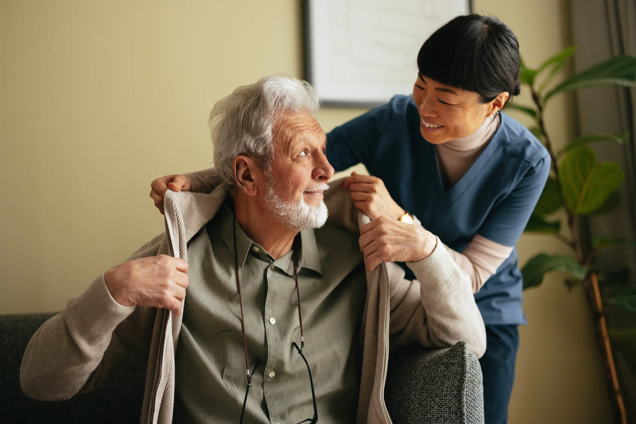 Caregiver helping a client with a sweater, both smiling